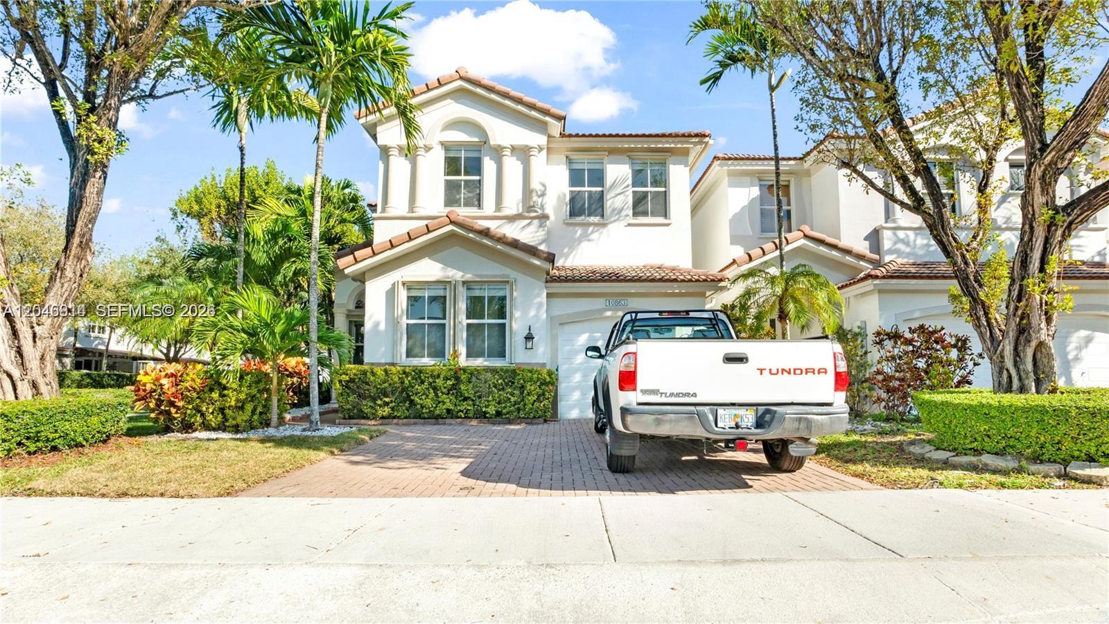 A white two-story house with a paved driveway and a parked pickup truck — 10863 NW 85th St # 0, Doral FL 33178, DORAL, FL