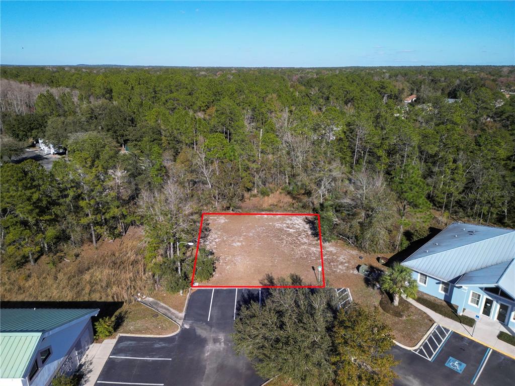 An aerial view shows a cleared, rectangular vacant lot bordered by parking lots and trees — 8401 S SUNCOAST BOULEVARD UNIT 3, HOMOSASSA, FL
