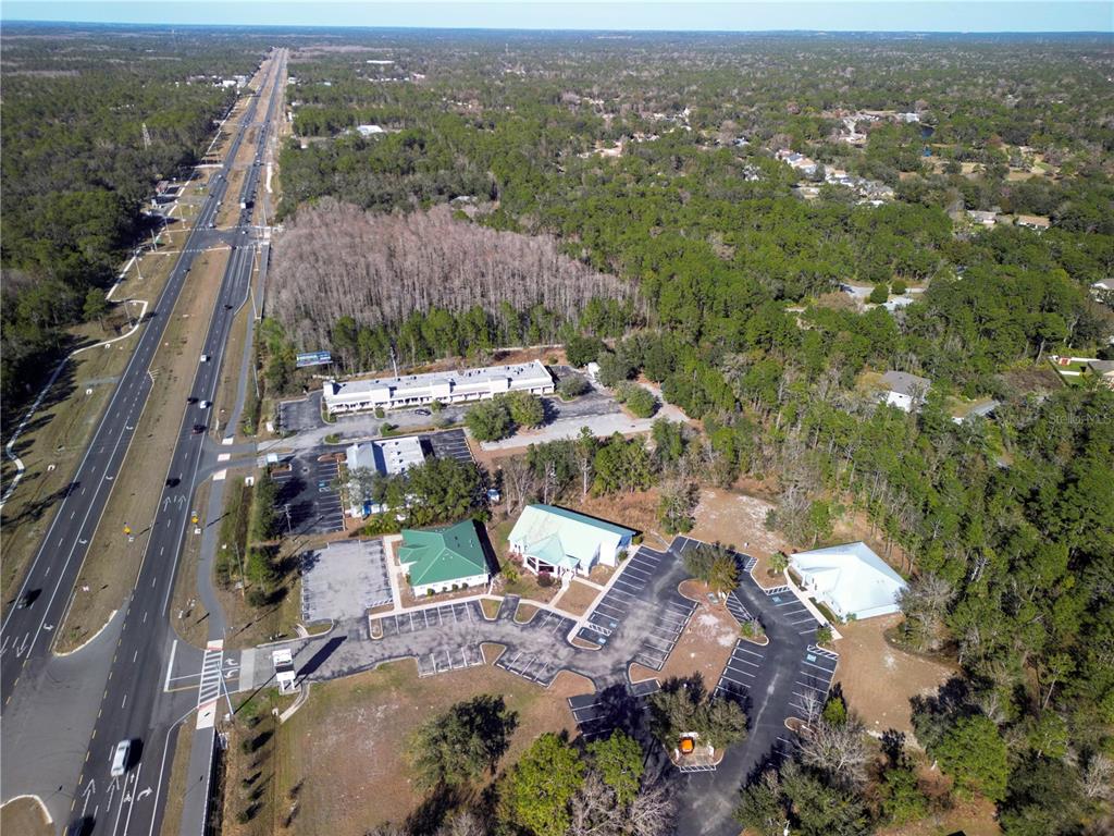 An aerial view shows several commercial buildings with parking lots situated next to a highway — 8401 S SUNCOAST BOULEVARD UNIT 3, HOMOSASSA, FL