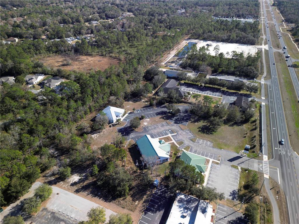 An aerial view shows several commercial buildings with parking lots situated next to a highway — 8401 S SUNCOAST BOULEVARD UNIT 3, HOMOSASSA, FL
