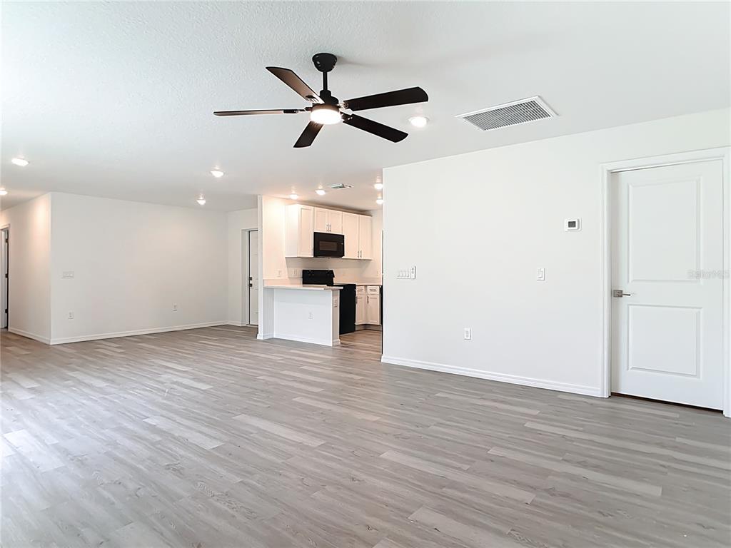 A living room with light wood-look flooring, a ceiling fan, and an open kitchen — 3067 QUARTER STREET, NORTH PORT, FL