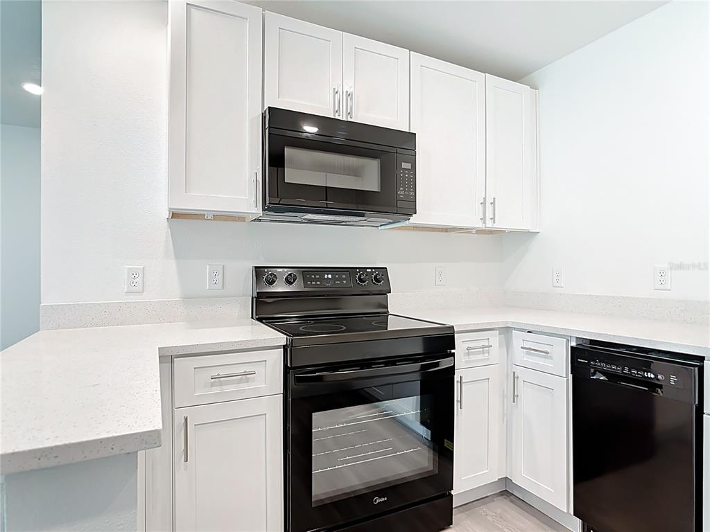 A kitchen features white cabinets, black appliances, and light-colored countertops — 3067 QUARTER STREET, NORTH PORT, FL