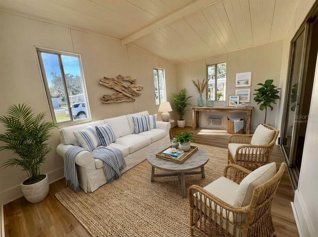 A sunroom features a white sofa, two rattan chairs, a round table, and wood flooring — 222 HAWTHORNE BOULEVARD, LEESBURG, FL