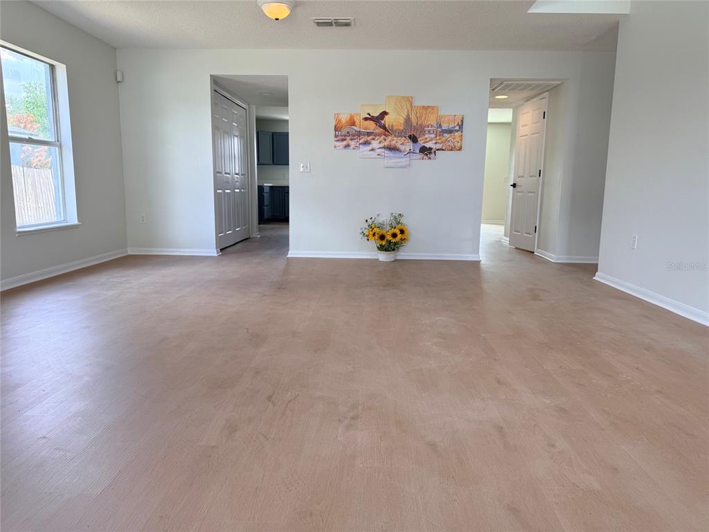A living room with light-colored flooring, white walls, a multi-panel wall art, and two doorways — 5871 WINDRIDGE DRIVE, WINTER HAVEN, FL