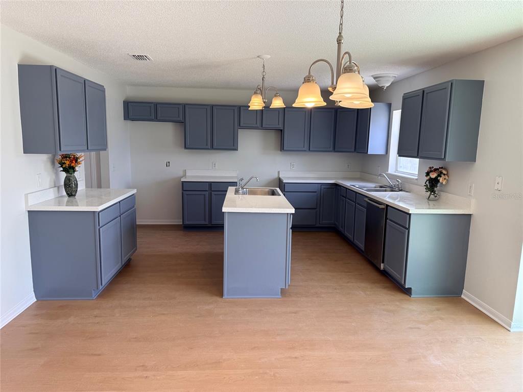 A kitchen features blue cabinets, white countertops, a center island, and light wood flooring — 5871 WINDRIDGE DRIVE, WINTER HAVEN, FL