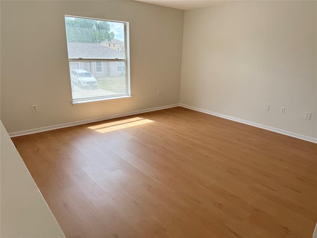 An empty room with light wood-look flooring, beige walls, and a single window — 5871 WINDRIDGE DRIVE, WINTER HAVEN, FL