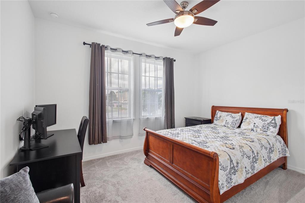A bedroom features a wooden sleigh bed, a desk with a monitor, and two windows — 5732 IRON BRAND ROAD, ST CLOUD, FL
