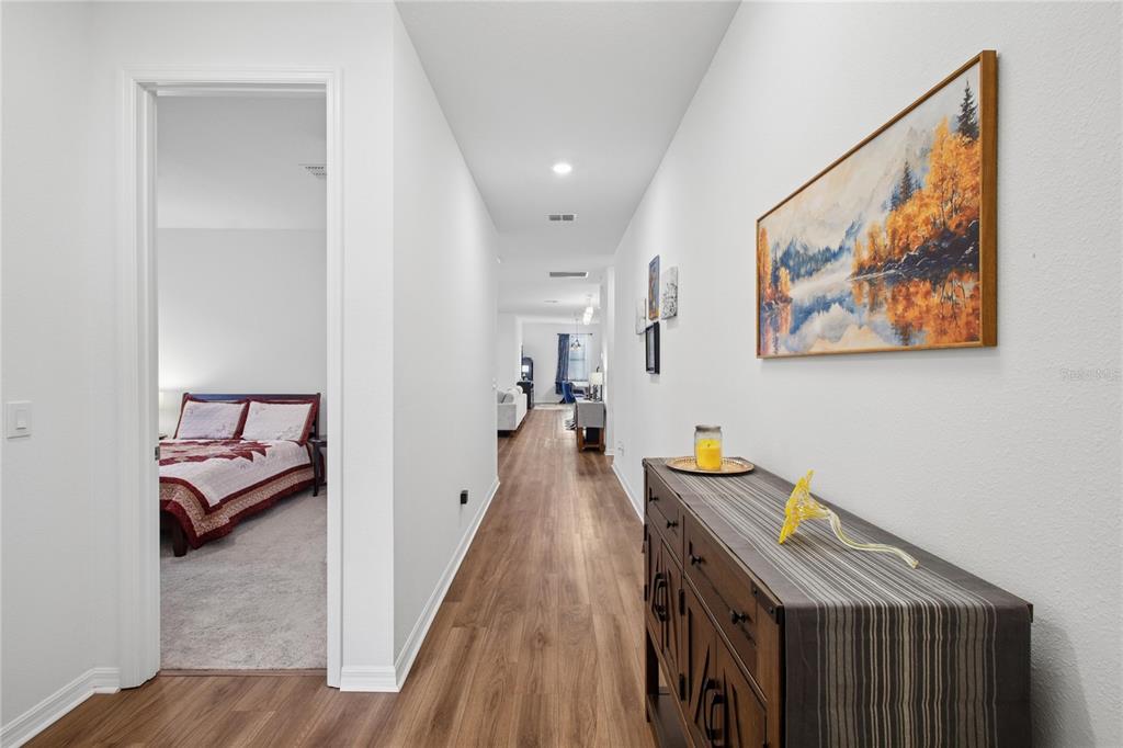 A hallway with wood-look flooring leads from a bedroom doorway toward an open living area — 5732 IRON BRAND ROAD, ST CLOUD, FL