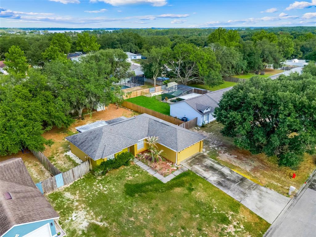 An aerial view shows a yellow single-story house with a gray roof and concrete driveway — 10752 CRESCENDO LOOP, CLERMONT, FL