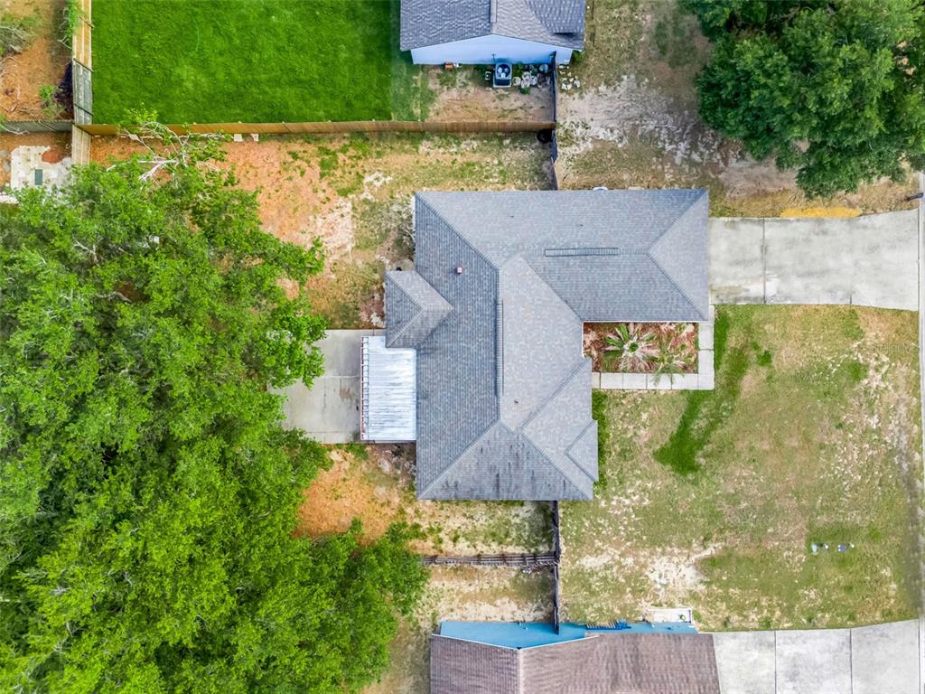 An aerial view shows a house with a gray roof, a large tree, and surrounding yards — 10752 CRESCENDO LOOP, CLERMONT, FL