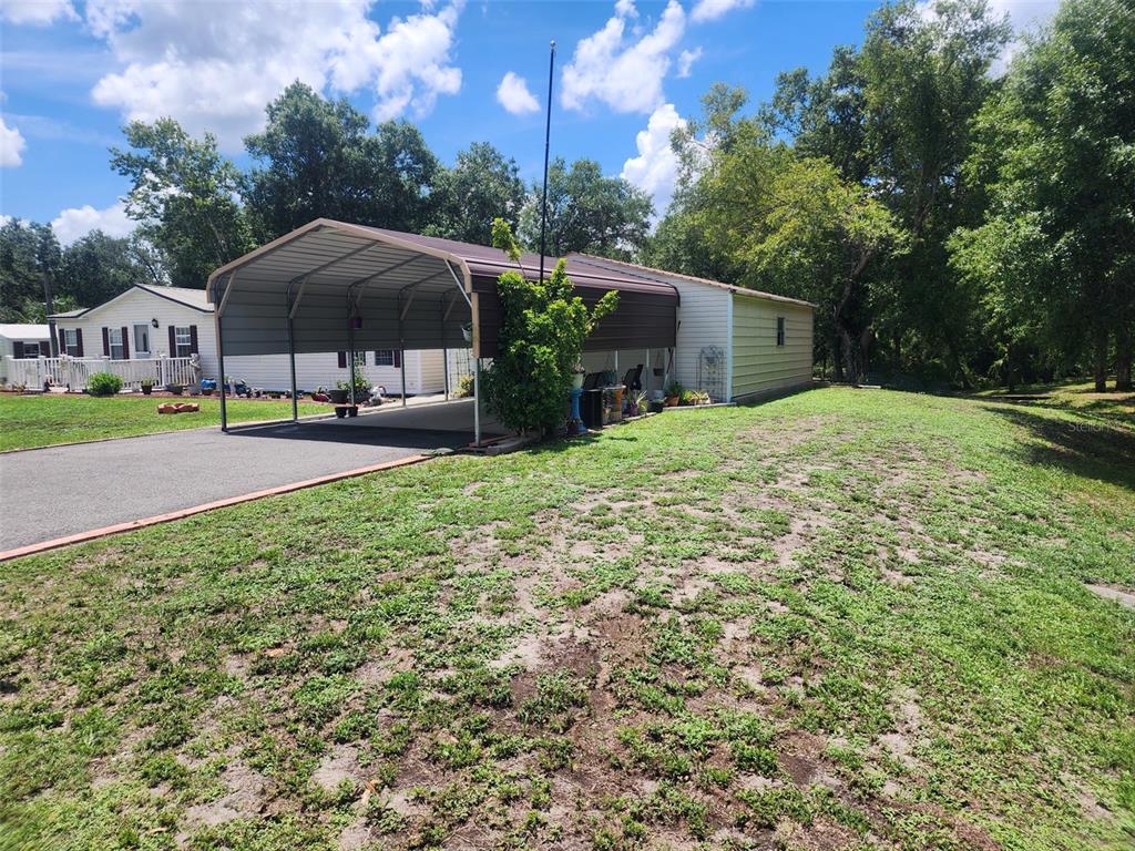 A metal carport is attached to the side of a light-colored mobile home — 12398 SW CRENSHAW AVENUE, ARCADIA, FL