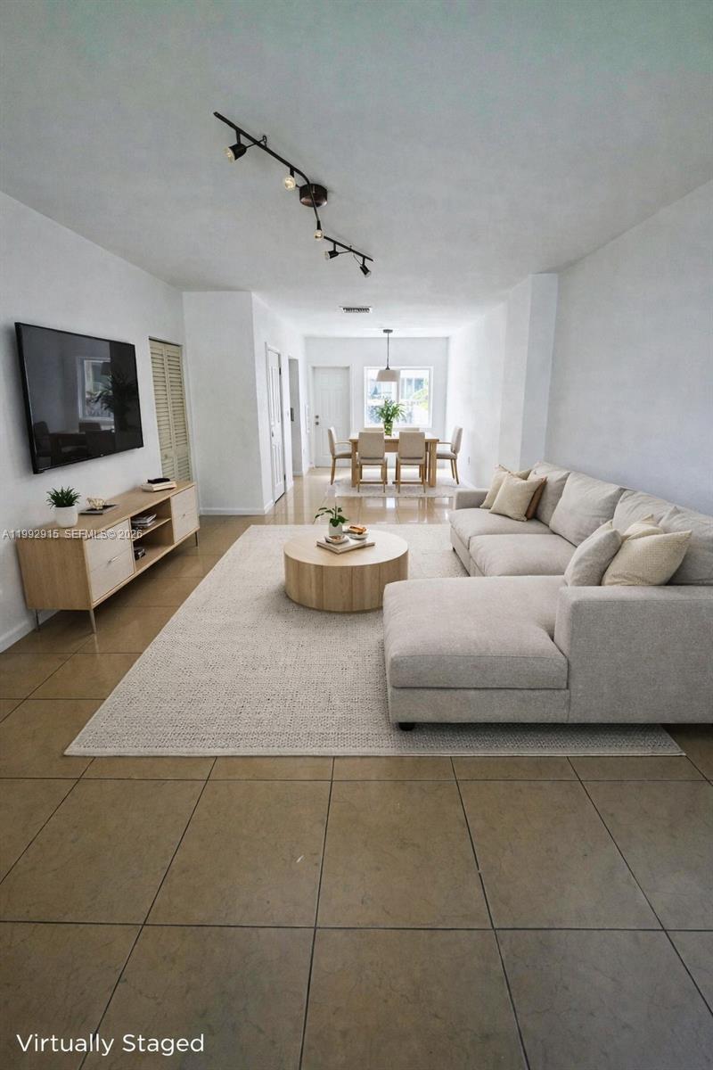 This virtually staged living and dining area features tile flooring and a neutral color palette — 440 NW 84th Ter # 440, Miami FL 33150, MIAMI, FL