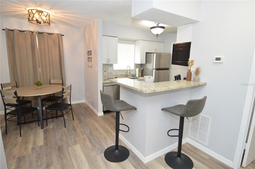 A dining area with a round table and a kitchen featuring a breakfast bar — 8754 MALLARD RESERVE DRIVE UNIT 202, TAMPA, FL