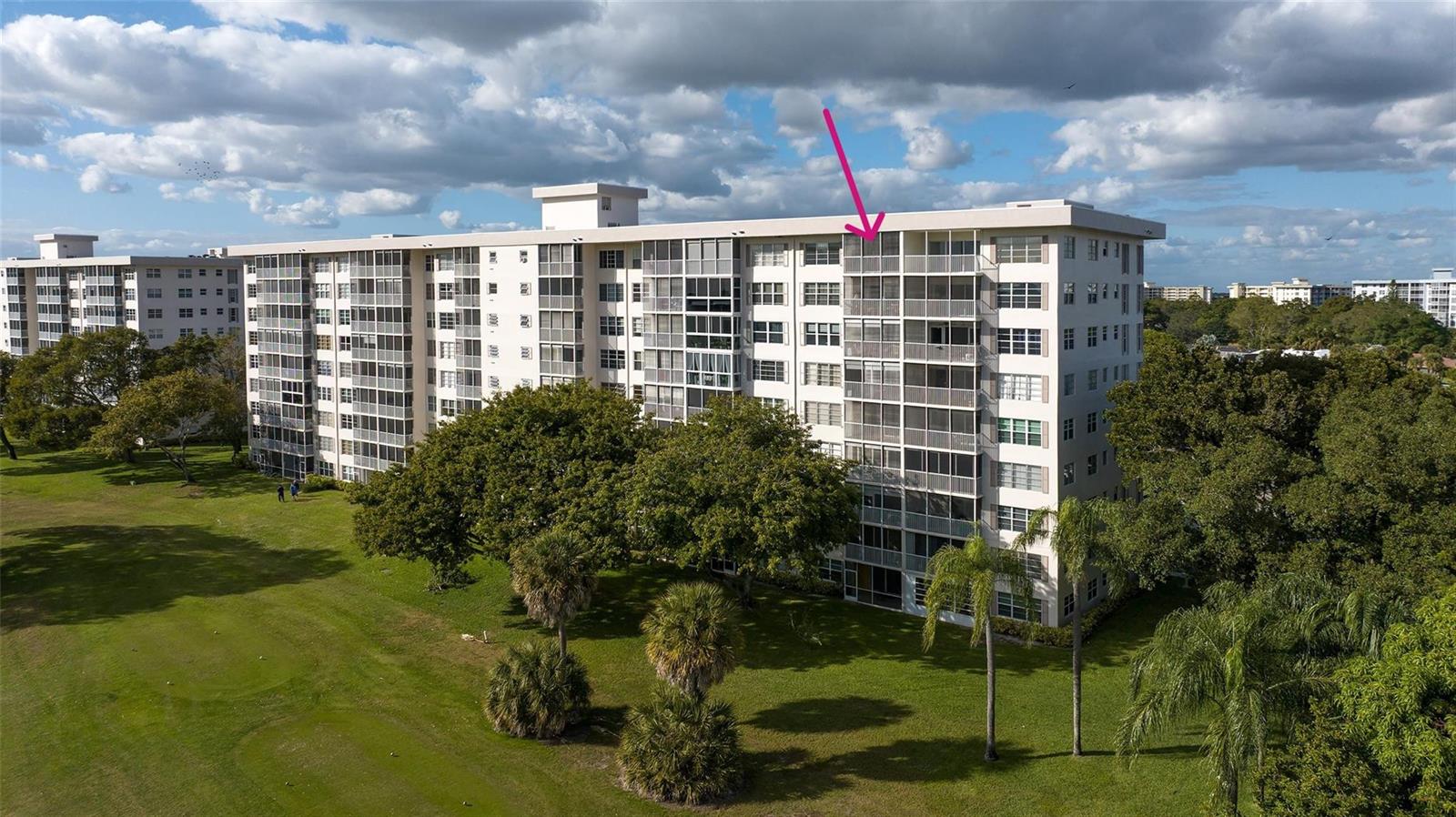 An aerial view shows the exterior of a multi-story apartment building with screened balconies — 3050 N Palm Aire Drive # 909, Pompano Beach FL 33069, POMPANO BEACH, FL