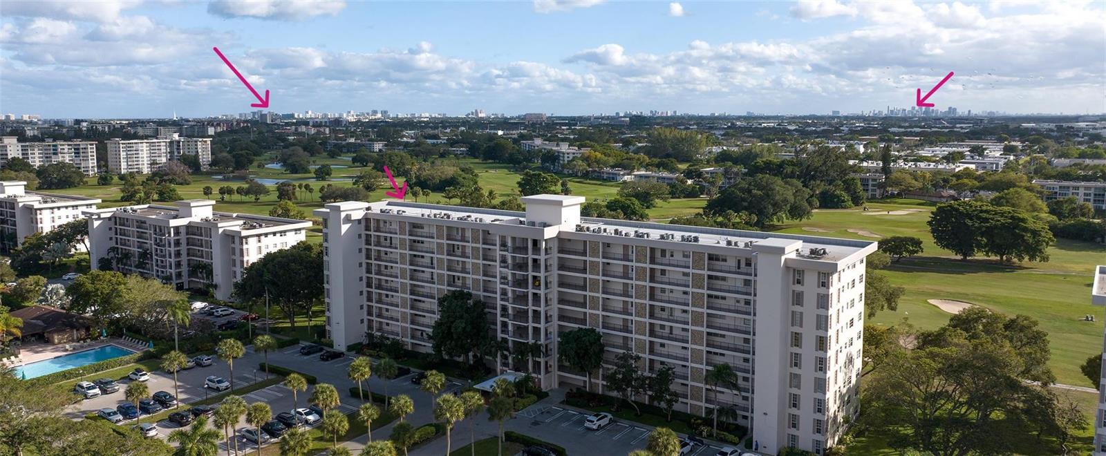 An aerial view shows a multi-story apartment building overlooking a golf course and city skyline — 3050 N Palm Aire Drive # 909, Pompano Beach FL 33069, POMPANO BEACH, FL