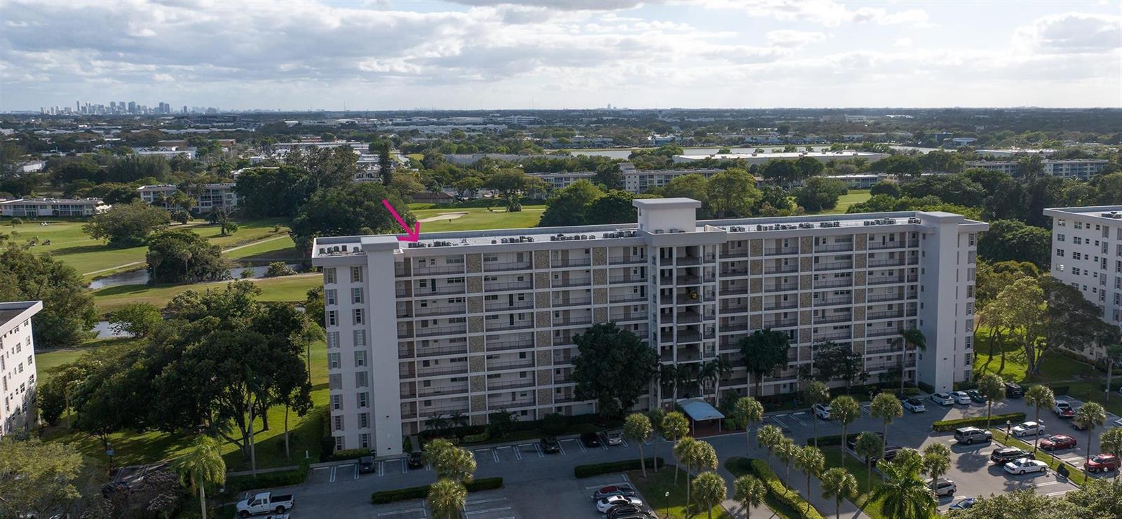 An aerial view shows a multi-story apartment building surrounded by a golf course and parking — 3050 N Palm Aire Drive # 909, Pompano Beach FL 33069, POMPANO BEACH, FL