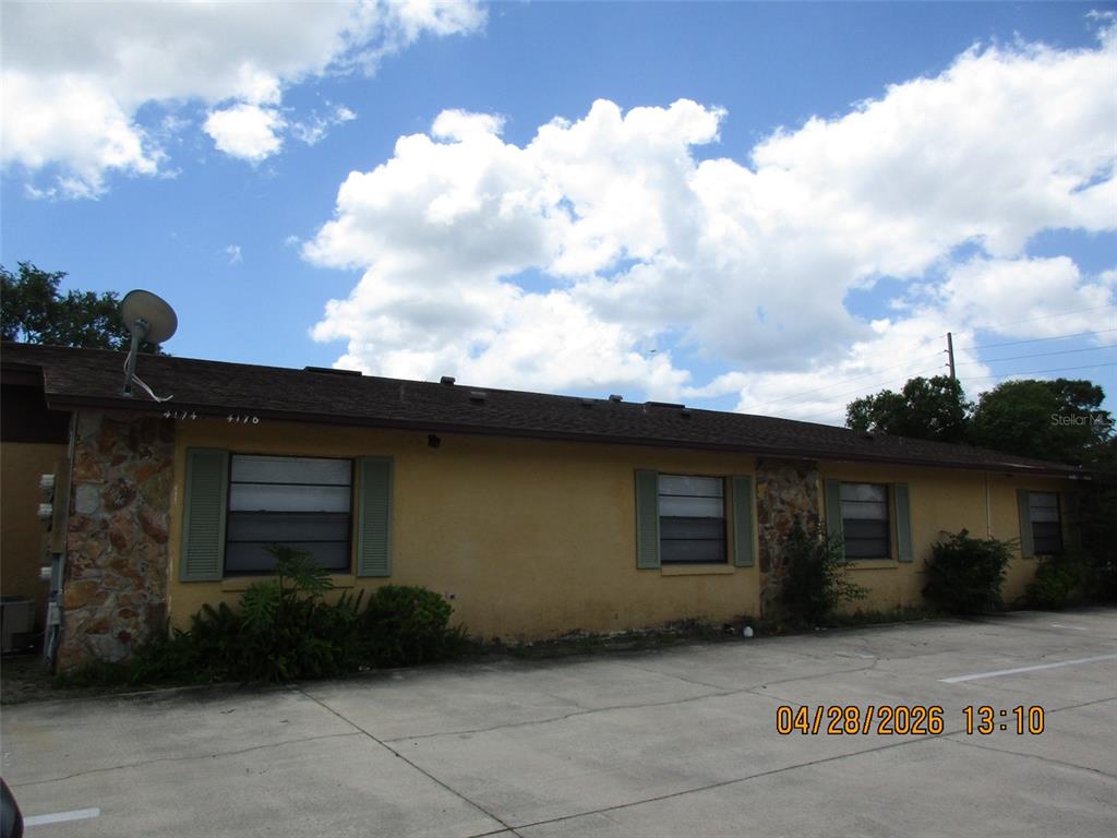 The exterior of a single-story, yellow stucco building with stone accents and a parking lot — 4174 CORSAIR AVENUE UNIT 4174, KISSIMMEE, FL