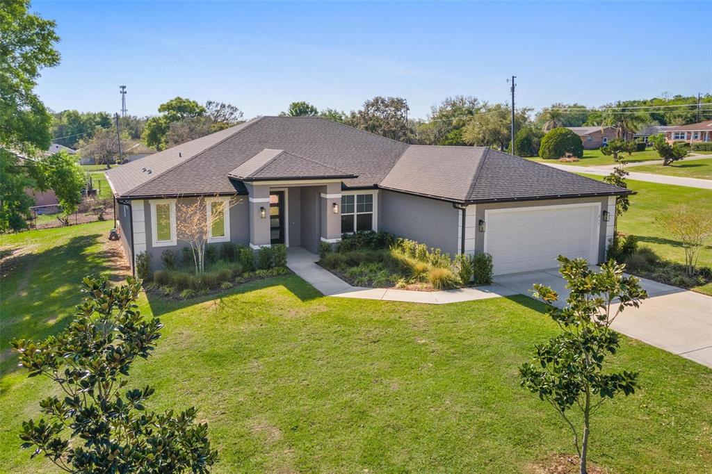 A single-story gray house with a dark shingled roof and a two-car garage — 415 N DIXIE DRIVE, HOWEY IN THE HILLS, FL