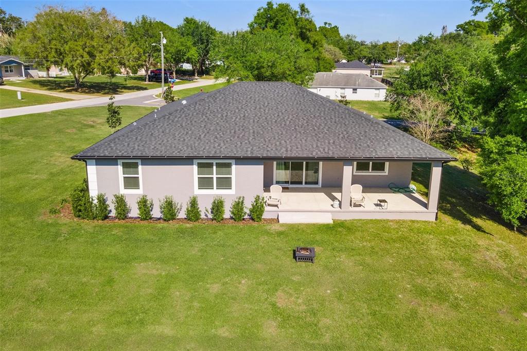 An aerial view of the back exterior of a gray house with a covered patio — 415 N DIXIE DRIVE, HOWEY IN THE HILLS, FL