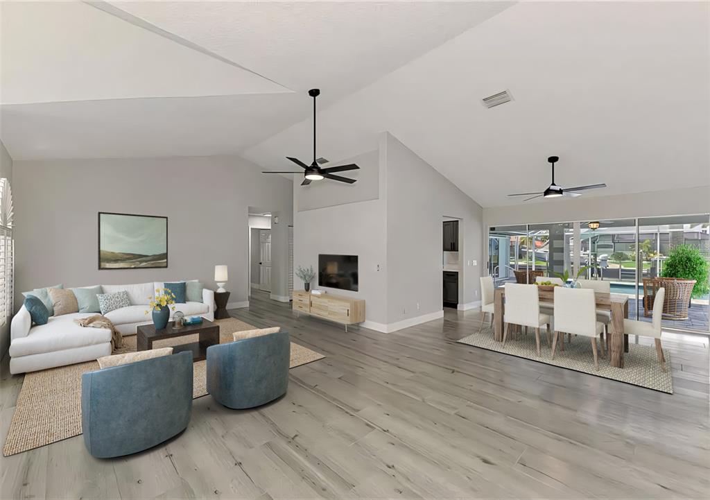 A bright open-concept living and dining area features vaulted ceilings, light wood flooring, and furniture — 3077 STONE STREET, PORT CHARLOTTE, FL