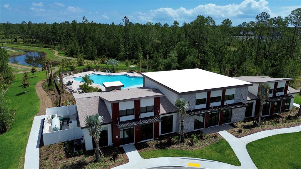 An aerial view of a modern community clubhouse with a swimming pool and surrounding forest — 305 FISHTAIL PLACE, PALM COAST, FL