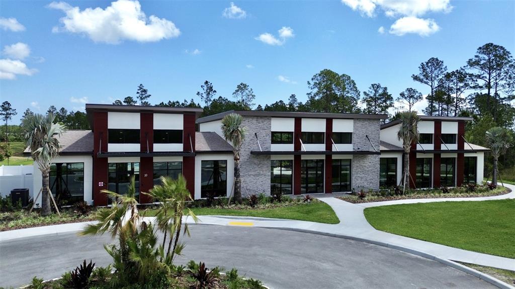 A modern commercial building with stone and dark red siding sits behind a paved driveway — 305 FISHTAIL PLACE, PALM COAST, FL