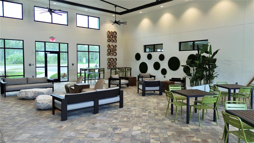A spacious, modern indoor-outdoor lounge area features stone flooring, contemporary furniture, and large windows — 305 FISHTAIL PLACE, PALM COAST, FL