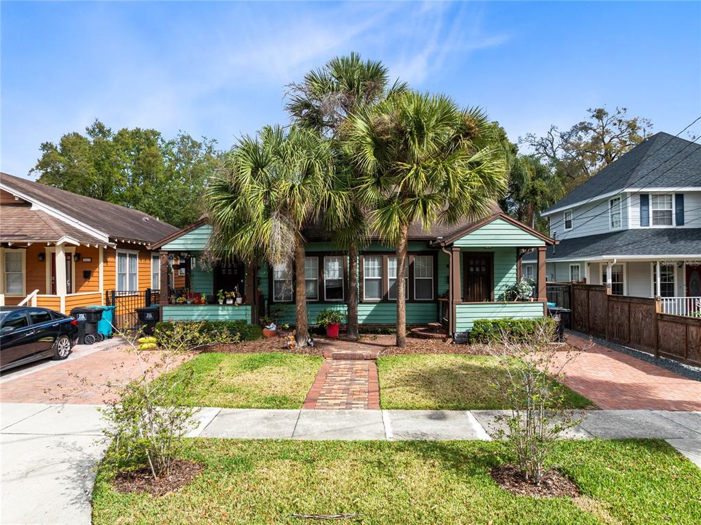 A single-story green house with a brick walkway and two palm trees in the yard — 1415 E AMELIA STREET, ORLANDO, FL