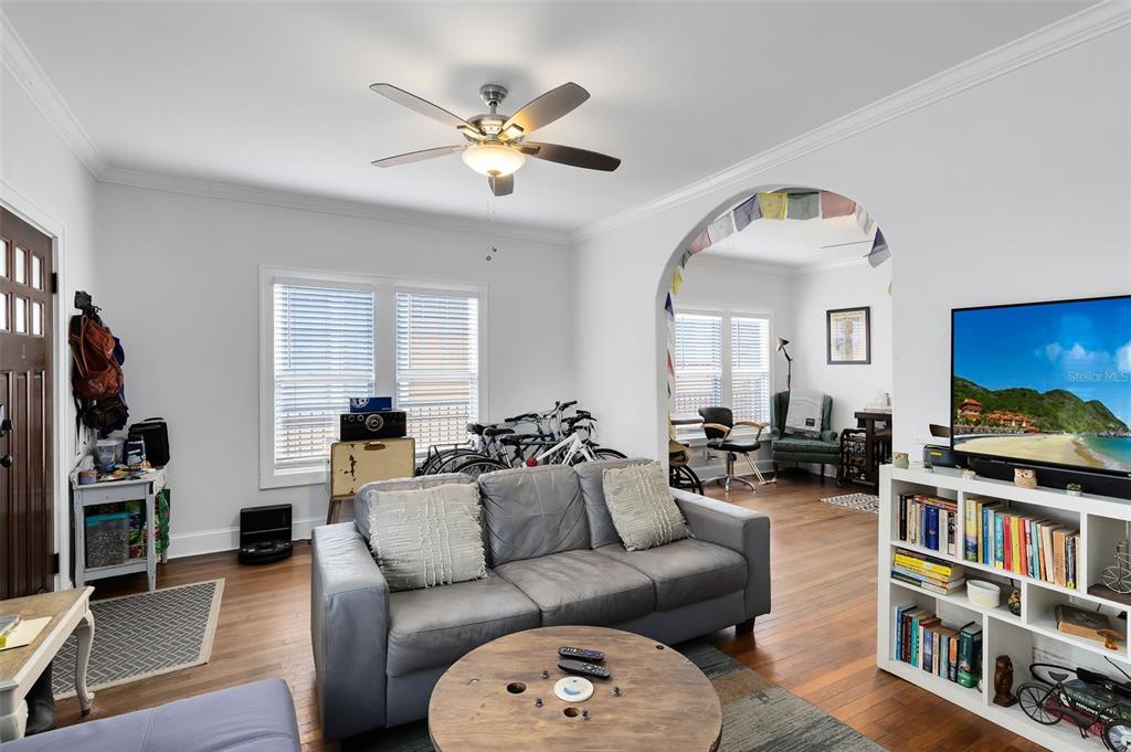 A living room features a grey sofa, a wooden coffee table, and an arched entryway — 1415 E AMELIA STREET, ORLANDO, FL
