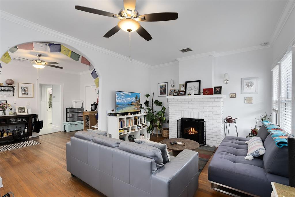 A living room features a white brick fireplace, a ceiling fan, and gray sofas — 1415 E AMELIA STREET, ORLANDO, FL