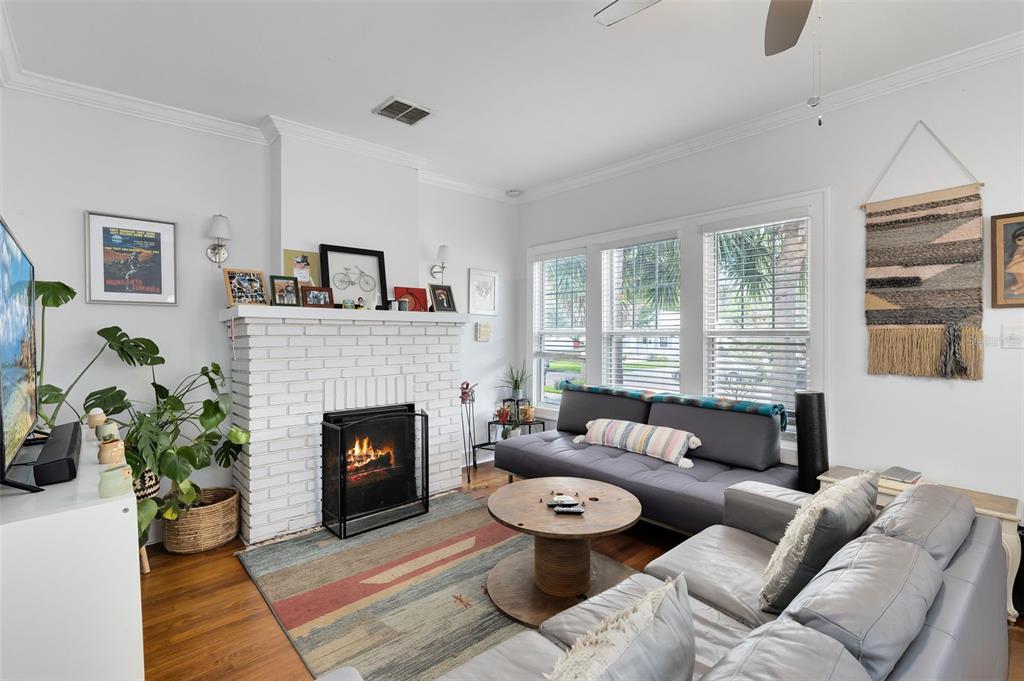 A living room features a white brick fireplace, gray sofas, and a round wooden coffee table — 1415 E AMELIA STREET, ORLANDO, FL