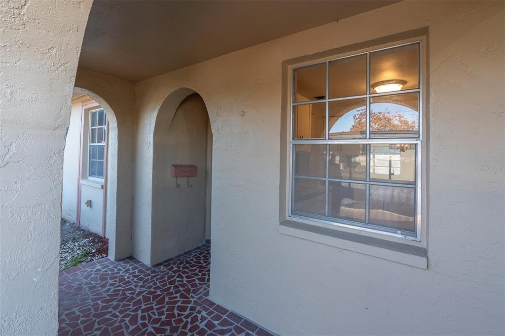A covered entryway features a tiled floor, arched openings, and a window with muntins — 4343 SUMMERSUN DRIVE UNIT 4343, NEW PORT RICHEY, FL