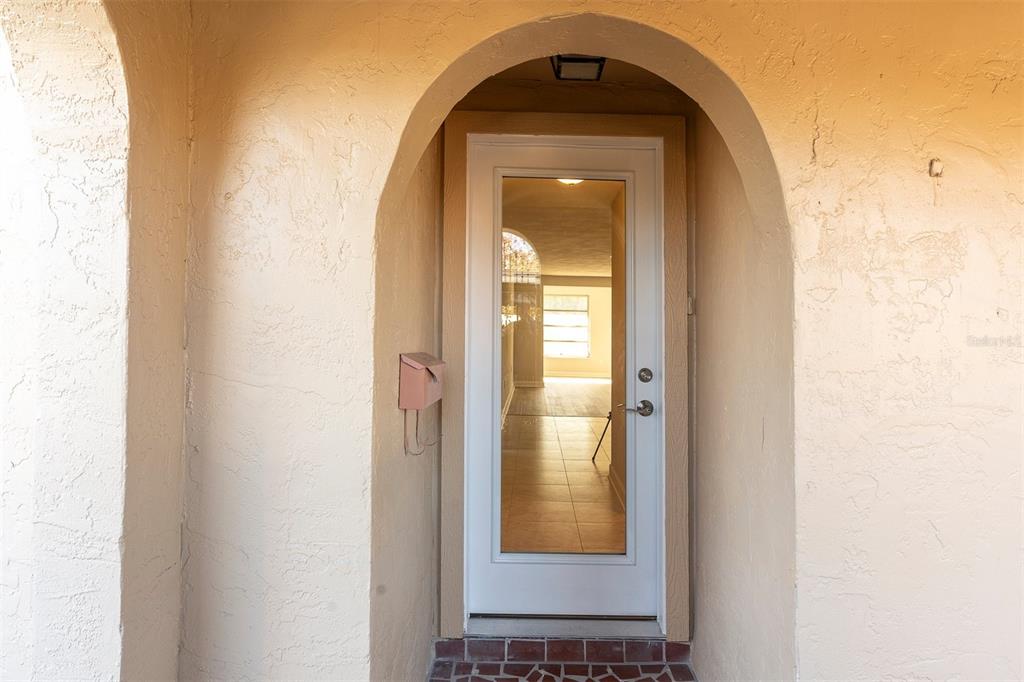 A white glass-paneled door is set within a beige arched entryway with a mailbox — 4343 SUMMERSUN DRIVE UNIT 4343, NEW PORT RICHEY, FL