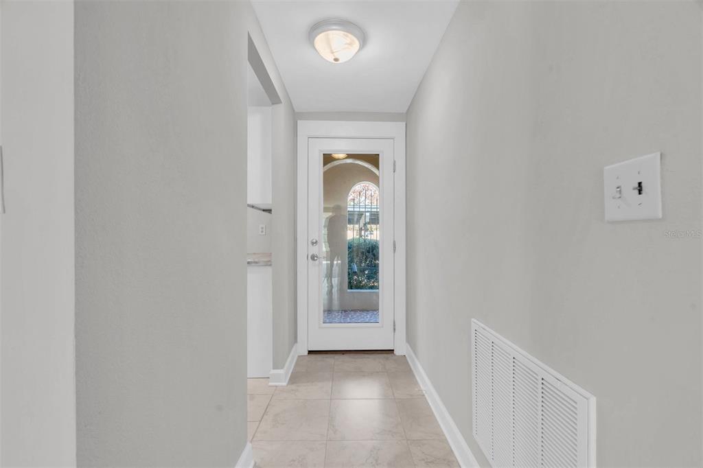 A hallway with light tile flooring leads to a white door with a glass panel — 4343 SUMMERSUN DRIVE UNIT 4343, NEW PORT RICHEY, FL