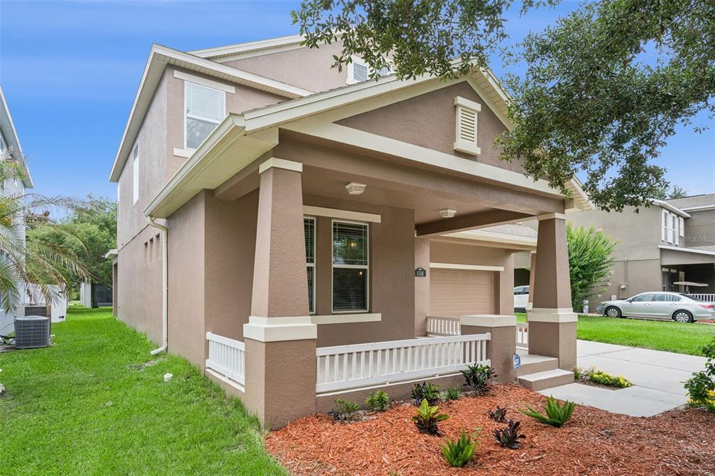 A two-story house with a tan stucco exterior, a front porch, and a paved driveway — 6316 MANUSCRIPT STREET, WINTER GARDEN, FL