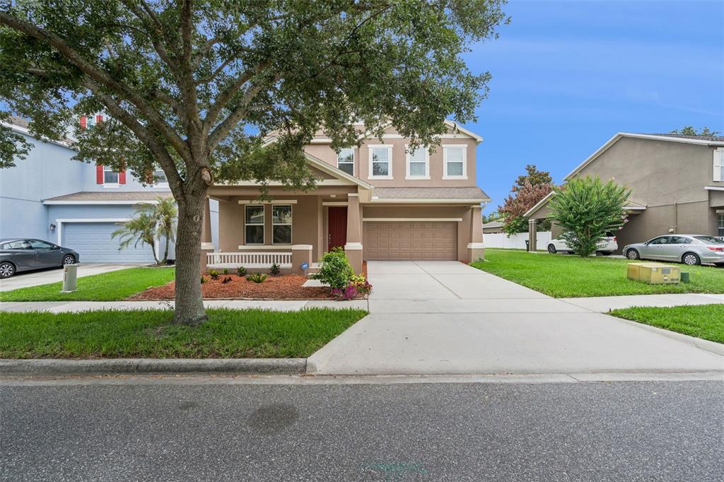 A two-story suburban house with a tan exterior, a red front door, and a driveway — 6316 MANUSCRIPT STREET, WINTER GARDEN, FL