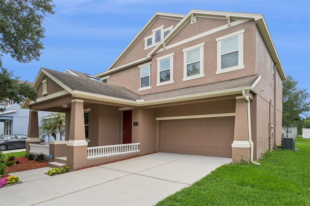 A two-story suburban house with a tan stucco exterior, a front porch, and a garage — 6316 MANUSCRIPT STREET, WINTER GARDEN, FL