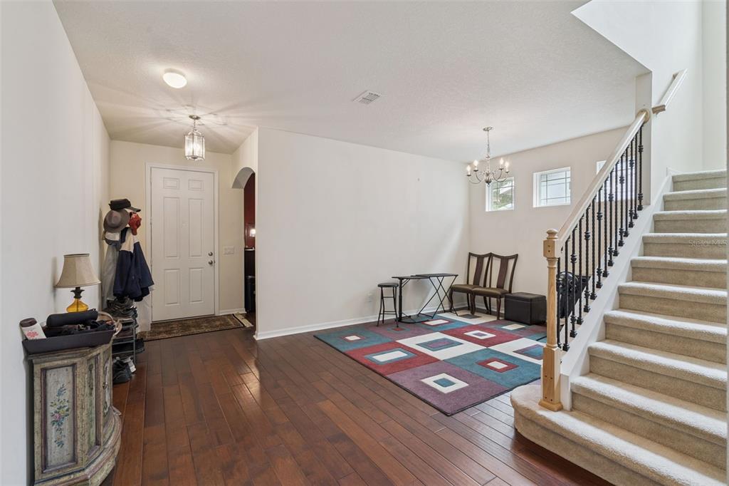 An entryway features hardwood floors, a carpeted staircase with a metal railing, and a rug — 6316 MANUSCRIPT STREET, WINTER GARDEN, FL