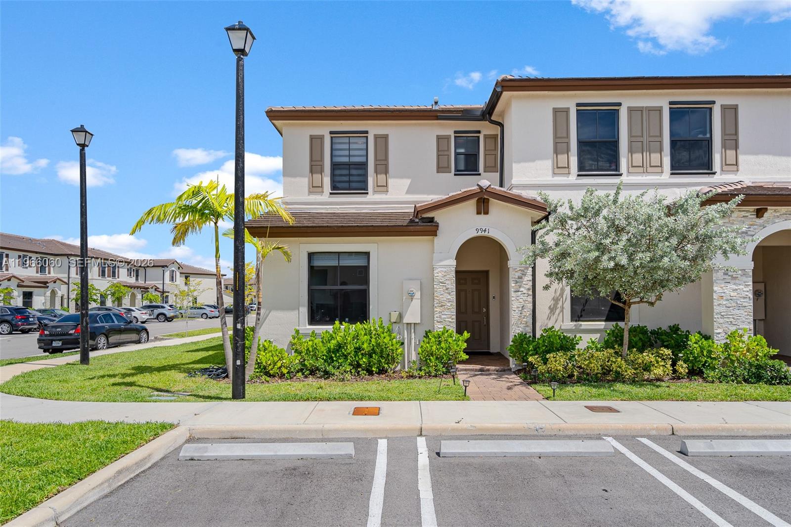 A two-story townhouse exterior features a beige stucco facade, brown shutters, and a stone-accented entryway — 9941 SW 231st Ln # 9941, Miami FL 33190, MIAMI, FL