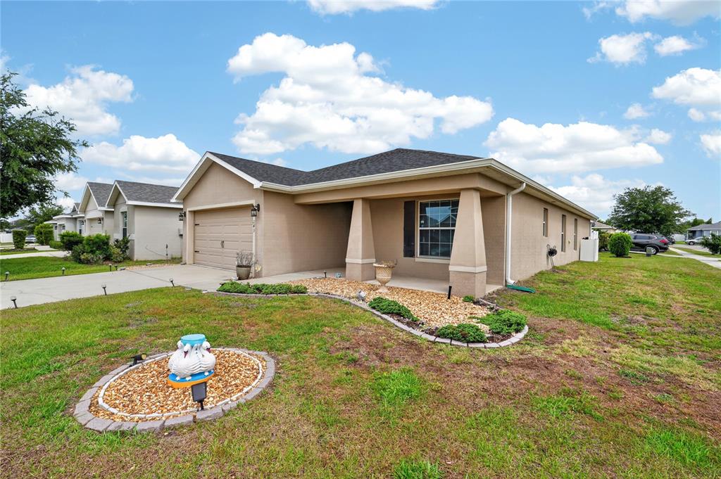 A single-story tan house with a two-car garage and a landscaped front yard — 243 SANDESTIN DRIVE, HAINES CITY, FL
