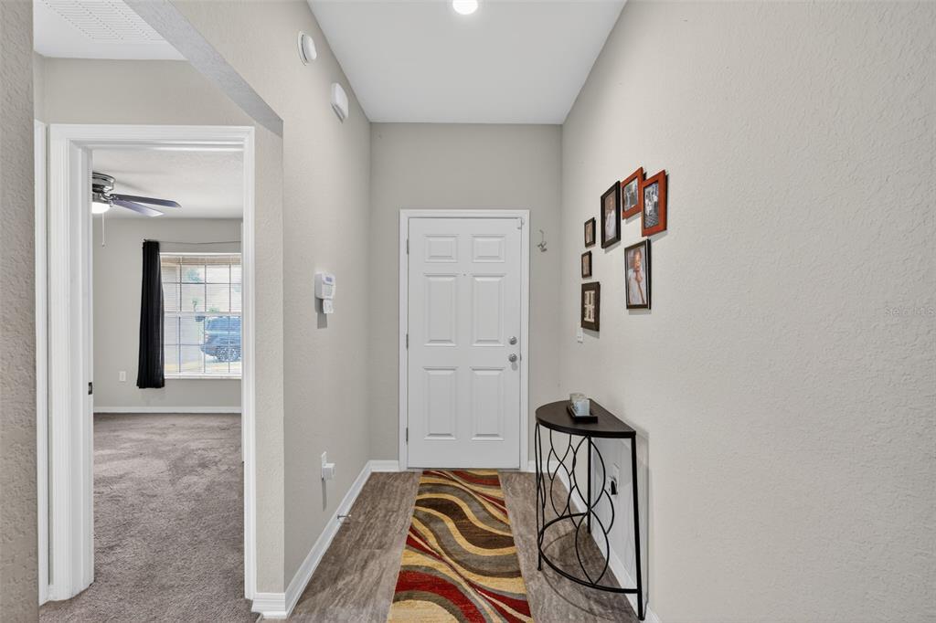 A foyer with wood-look flooring, a white front door, and a small console table — 243 SANDESTIN DRIVE, HAINES CITY, FL