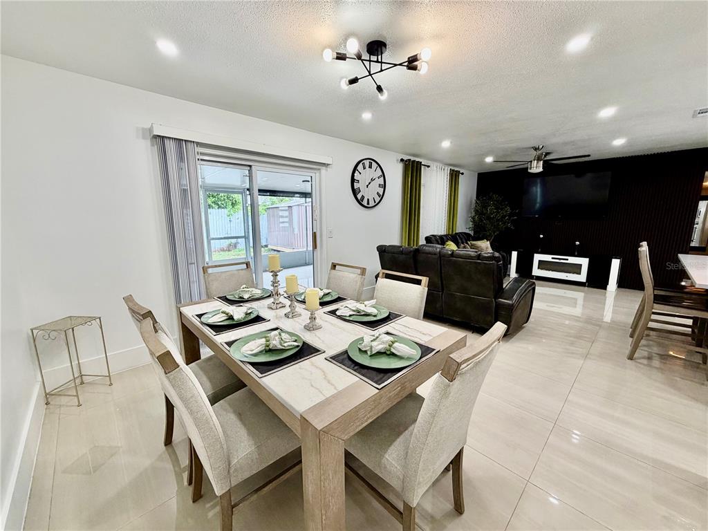 A dining area with a light-colored table and chairs sits adjacent to a living room — 4911 SHETLAND AVENUE, TAMPA, FL
