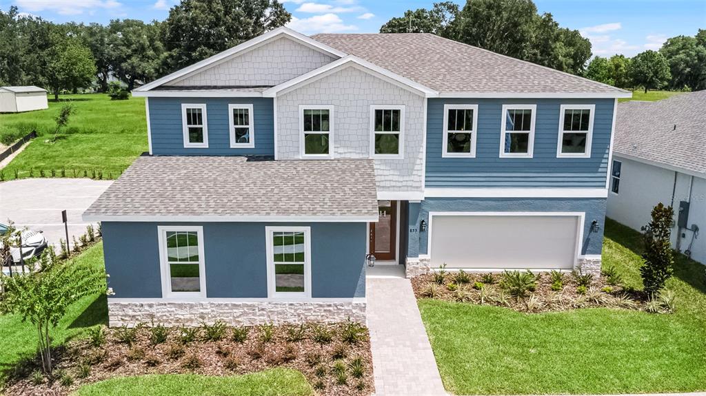 A two-story house with blue siding, white stone accents, and a two-car garage — 724 MYSTIC GARDENS DRIVE, APOPKA, FL