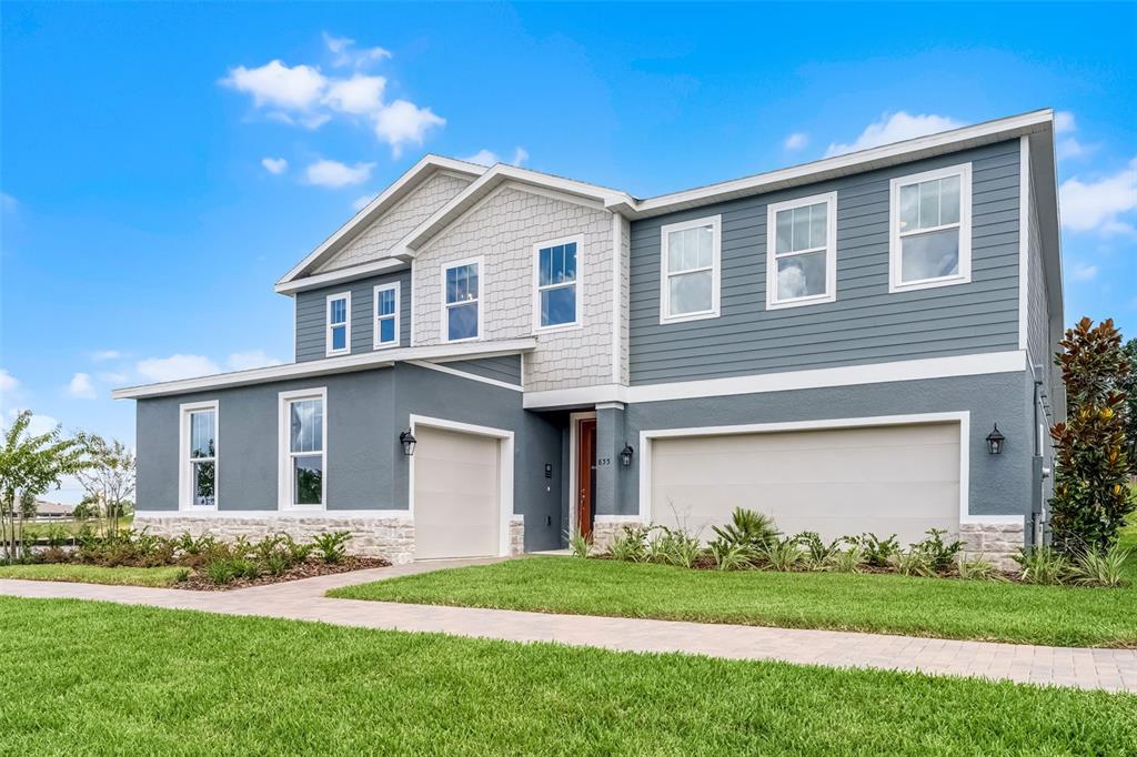 A two-story house with gray siding, stone accents, and a three-car garage — 724 MYSTIC GARDENS DRIVE, APOPKA, FL