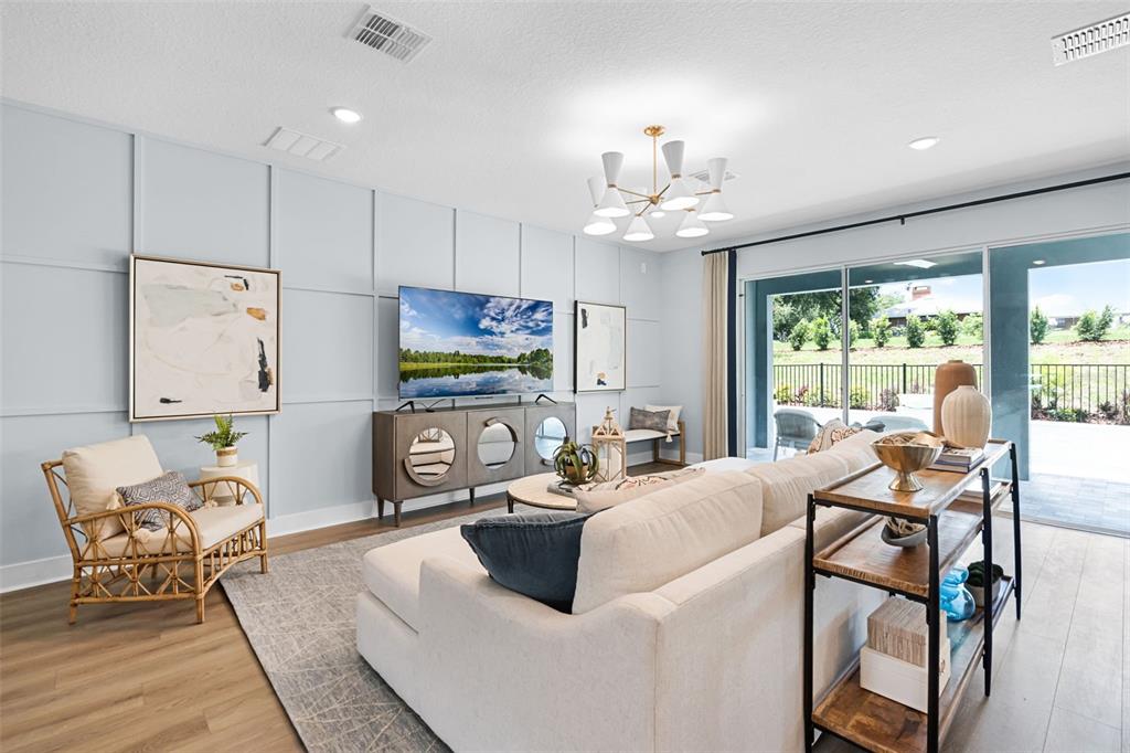 A living room features a light blue paneled wall, a large sectional sofa, and sliding doors — 724 MYSTIC GARDENS DRIVE, APOPKA, FL