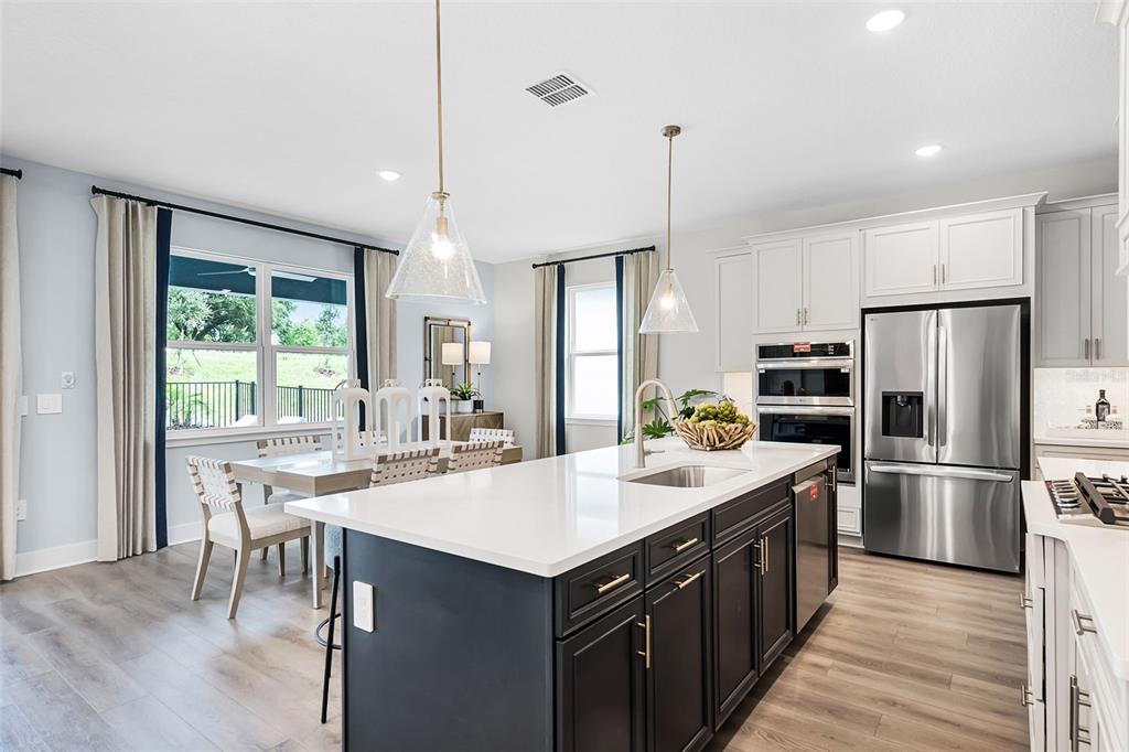 A kitchen features a dark blue island with a white countertop and stainless steel appliances — 724 MYSTIC GARDENS DRIVE, APOPKA, FL
