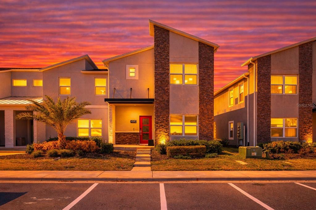 A modern two-story house with stone accents and a red front door at sunset — 1070 SPLASH SHOT PLACE, DAVENPORT, FL