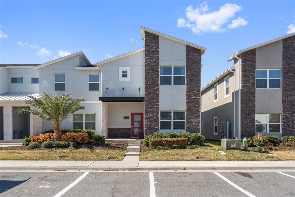 A two-story townhouse with a red front door and stone veneer accents on the exterior — 1070 SPLASH SHOT PLACE, DAVENPORT, FL