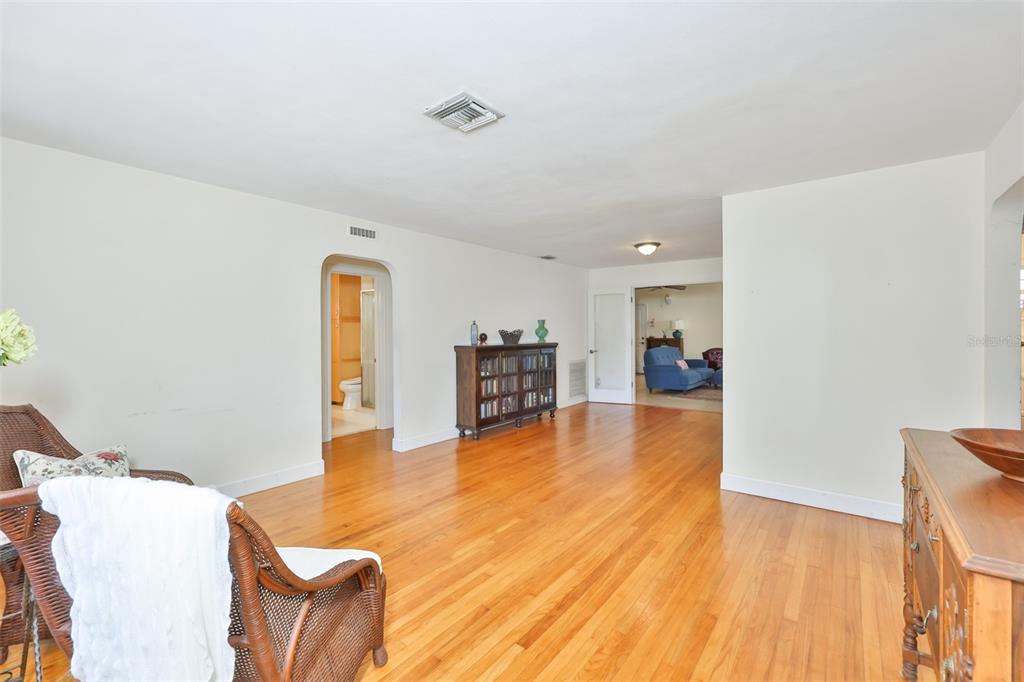 A living room with hardwood floors, a wooden bookshelf, and an arched doorway to a bathroom — 7508 4TH AVENUE N, ST PETERSBURG, FL