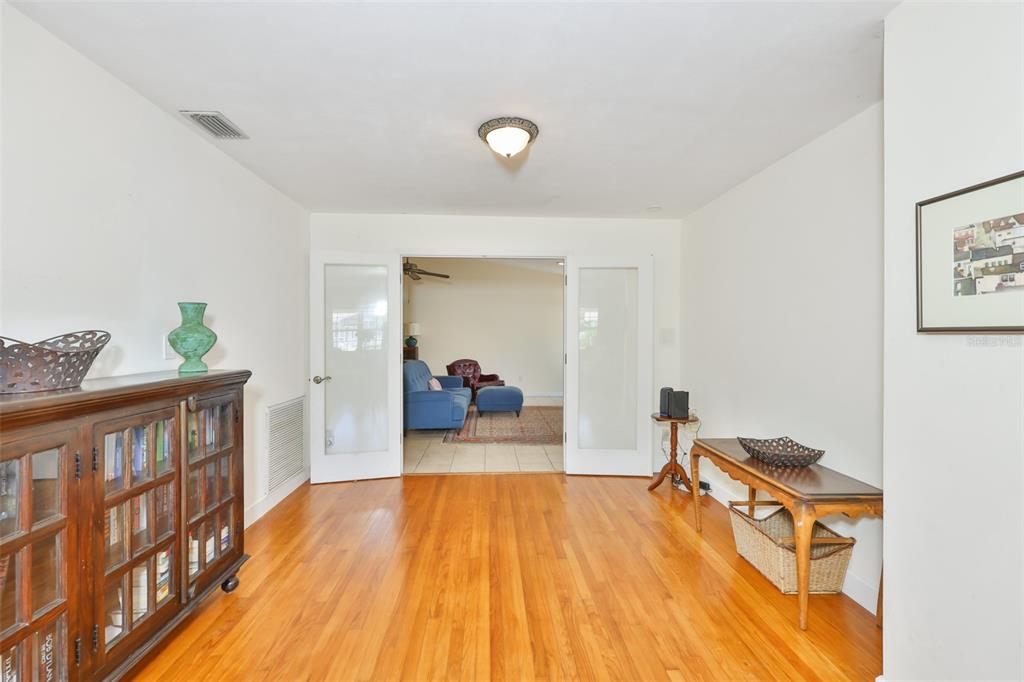 A room with hardwood floors, a wooden bookcase, and French doors leading to another space — 7508 4TH AVENUE N, ST PETERSBURG, FL